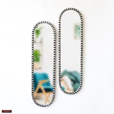 a pair of mirrors sitting on top of a white wall next to a blue chair