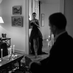 a woman standing in front of a mirror with candles on the floor next to her