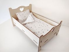 a small wooden bed with two pillows on it's sides and a heart shaped pillow in the middle