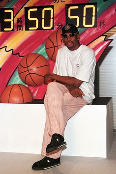 a man sitting on top of a white counter next to a basketball ball and sign