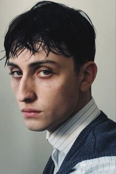 a close up of a person wearing a sweater and tie with hair in the wind