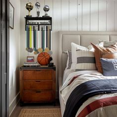 a bed room with a neatly made bed and a basketball on top of the headboard