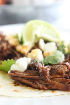 a close up of a tortilla with meat, cheese and cilantro