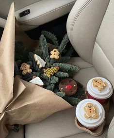 two cups of coffee sitting on top of a car seat next to cookies and christmas decorations