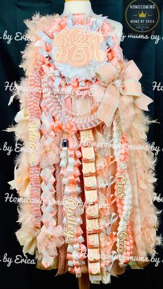 an orange and white dress with feathers on the bottom is displayed in front of a black backdrop