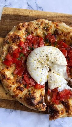 a pizza with tomatoes, cheese and herbs on it sitting on a cutting board next to a knife