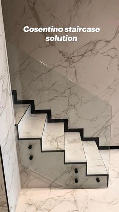 marble stairs with black handrails in a white and gray room, leading up to the second floor