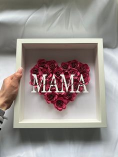 a heart shaped box with the word mama spelled in white letters and red roses inside