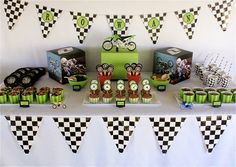 a table topped with lots of cupcakes and cake next to a race car