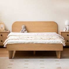 a bed with a teddy bear sitting on top of it next to two nightstands