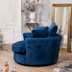 a living room with a blue chair, mirror and vase on the floor in front of it