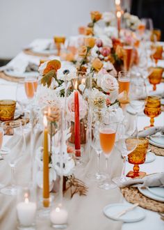 a long table is set with candles, plates and wine glasses for an elegant dinner