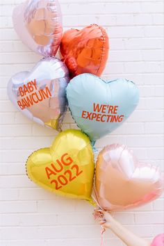 five heart shaped balloons with the words we're expecting on them