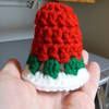 a hand holding a small crocheted christmas hat