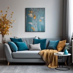 a grey couch with blue and yellow pillows in a living room next to a window