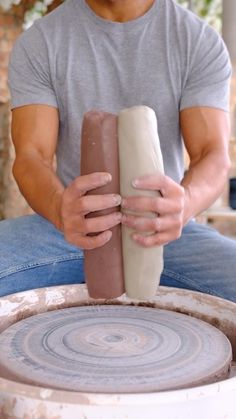 a man is sitting on the ground making something out of clay with his hands and fingers