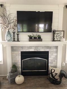 a fireplace with a flat screen tv above it and other decorations on the mantel