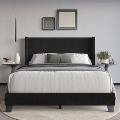 a bed with white sheets and black headboard in a gray room next to a round rug