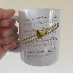 a person holding a coffee mug with musical notes on it and a trumpet in the middle