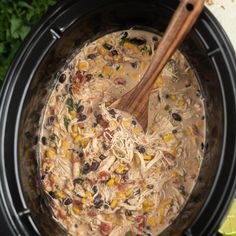 a crock pot filled with chicken, black beans and corn next to a lime wedge