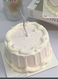 a white cake sitting on top of a table next to a box of candles and a candle holder