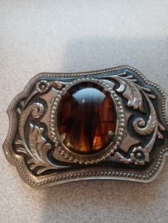 vintage silver tone belt buckle with natural stone cabochaon. VINTAGE SILVER TONE CABOCHON IN MIDDLE RESEMBLES TIGER'S EYE MINERAL WITH STRIATIONS  OF SOMETHING ELSE MIXED IN. I REALLY DON'T KNOW WHTAT THE ENTIRE STONE IS, BUCKLE MEASURES 3 1/2" X 2 1/2" SOME CORROSION EVIDENT ON METAL BRACKET HOLDING STONE IN ( SHOWS IN PHOTOS) VERY NICE PIECE FAST SHIPPING  THANKS FOR LOOKING Big Belt Buckle, Vintage Belt With Antique Buckle, Vintage Silver Belt Buckles For Festival, Vintage Brown Belt Buckles With Silver Buckle, Vintage Silver Belt Buckles For Rodeo, Big Buckle Belt, Antique Silver Buckle Belt Buckles For Ranch, Cowboy Belt, Silver Belt Buckle