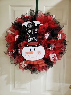 a red and black mesh wreath with a snowman face on it's front door