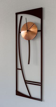 a metal clock mounted to the side of a wall next to a white wall with an abstract design on it