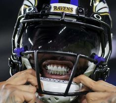 a close up of a person wearing a football helmet and holding his teeth to their face