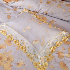 a yellow flowered comforter and pillow on a bed