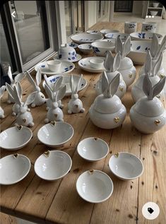 the table is set with many white dishes and bunny ears on each plate, along with other plates