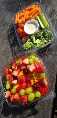 two plastic containers filled with different types of fruit and veggies on top of a wooden table