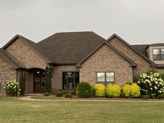 a large brick house with lots of flowers in the front yard