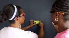 two women are looking at something on the wall while one woman is holding a camera