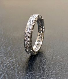 a white gold wedding ring with diamonds on it's sides, sitting on a black surface