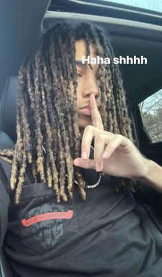 a man with dreadlocks sitting in the back seat of a car pointing to his finger