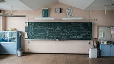 an empty room with a chalkboard and refrigerator