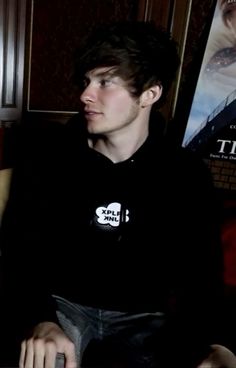 a young man sitting in front of a movie poster