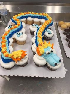 cupcakes with frosting shaped like animals and dragon on them are sitting on a tray