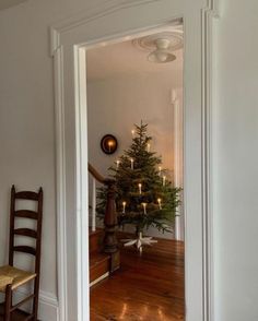 a small christmas tree sitting in the corner of a room next to a wooden chair