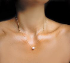 a woman wearing a necklace with a diamond on it