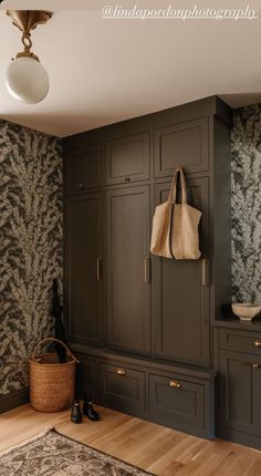 a room with wooden flooring and wallpaper on the walls, including two large cupboards