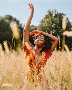 a woman standing in tall grass holding her arms up