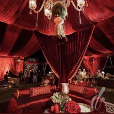 a red tent with chandeliers and flowers on it