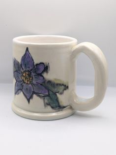 a white coffee cup with purple flowers painted on it