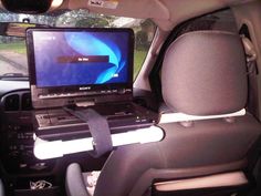 a laptop computer sitting on top of a desk in the back seat of a car