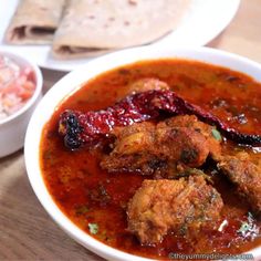 there is a bowl of food with meat and vegetables in it on the table next to some pita bread