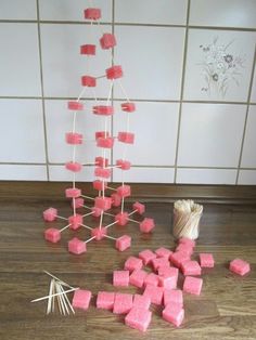 pink marshmallows are arranged on the floor next to a vase and sticks