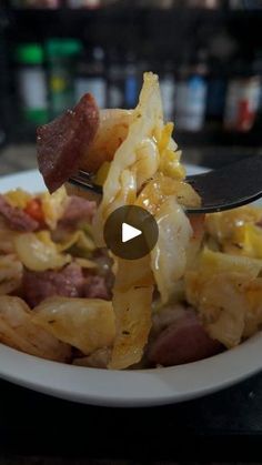 a white plate topped with pasta and meat next to a fork on top of a table