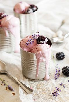 two tins filled with ice cream next to blackberries and lavender sprigs